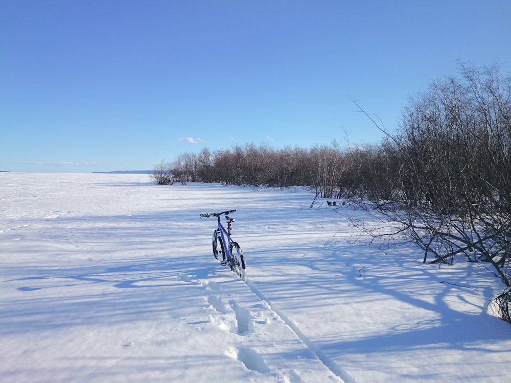 person riding on bicycle on snow covered field during daytime