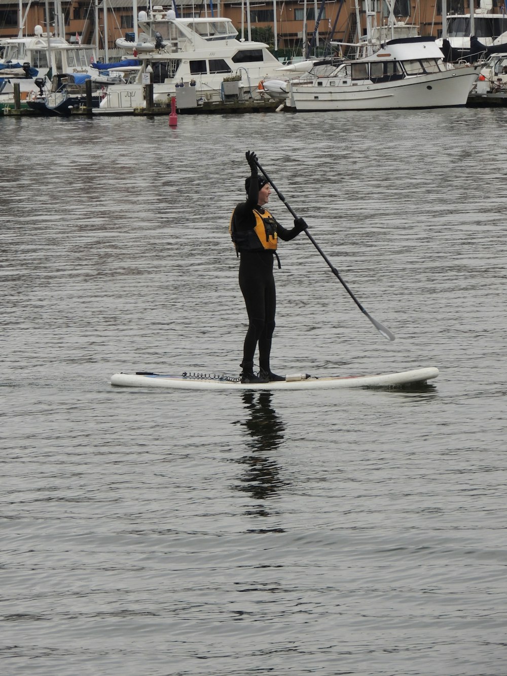 man in black wet suit riding on white surfboard during daytime