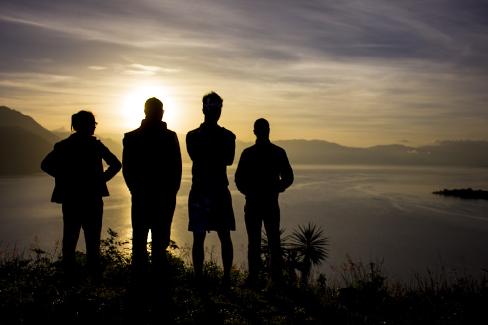 silhouette of 3 men standing on mountain during sunset