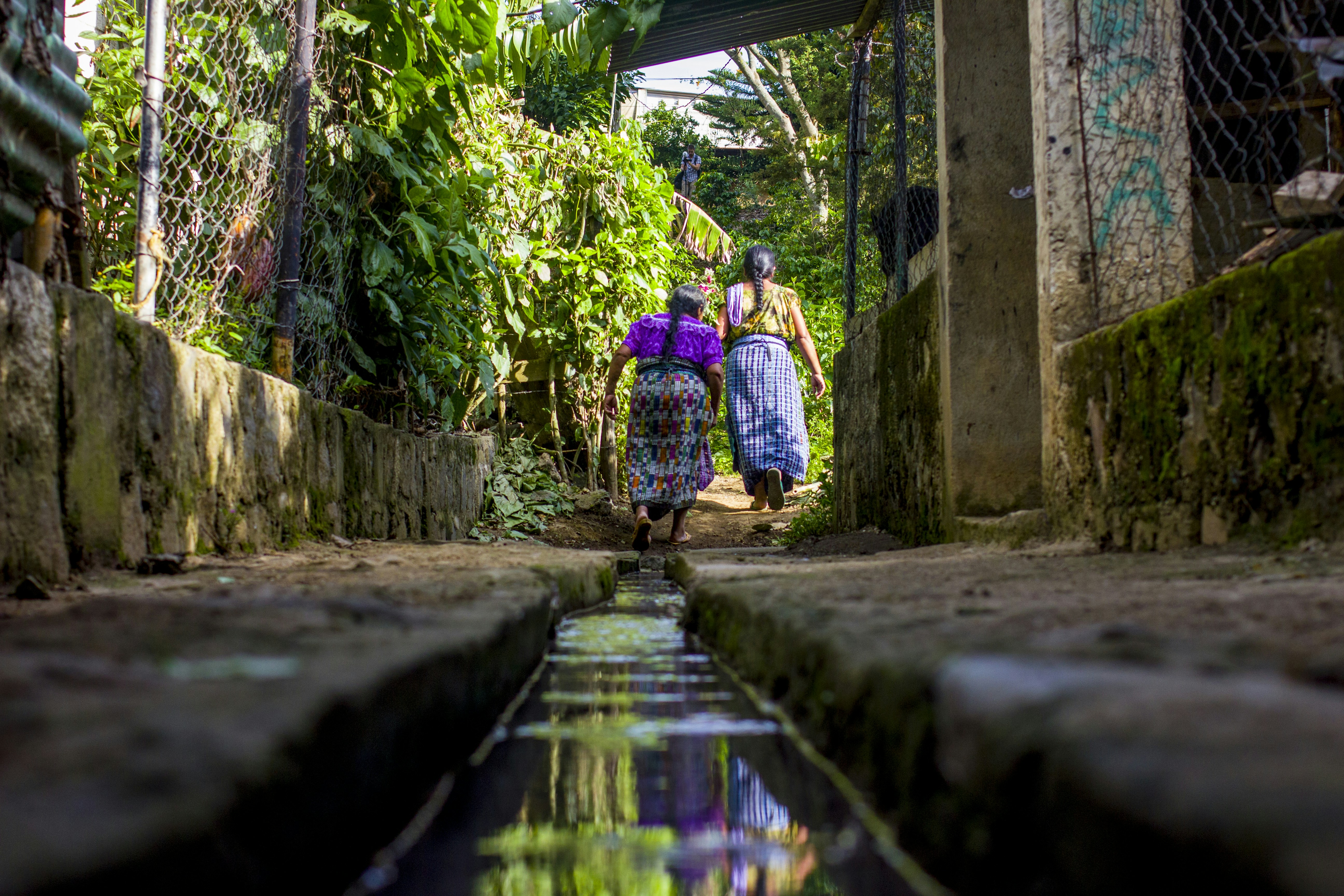 woman in blue and white dress walking on gray concrete pathway during daytime