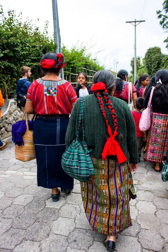 people in red and blue traditional dress walking on street during daytime in Santa Catarina Palopó Guatemala