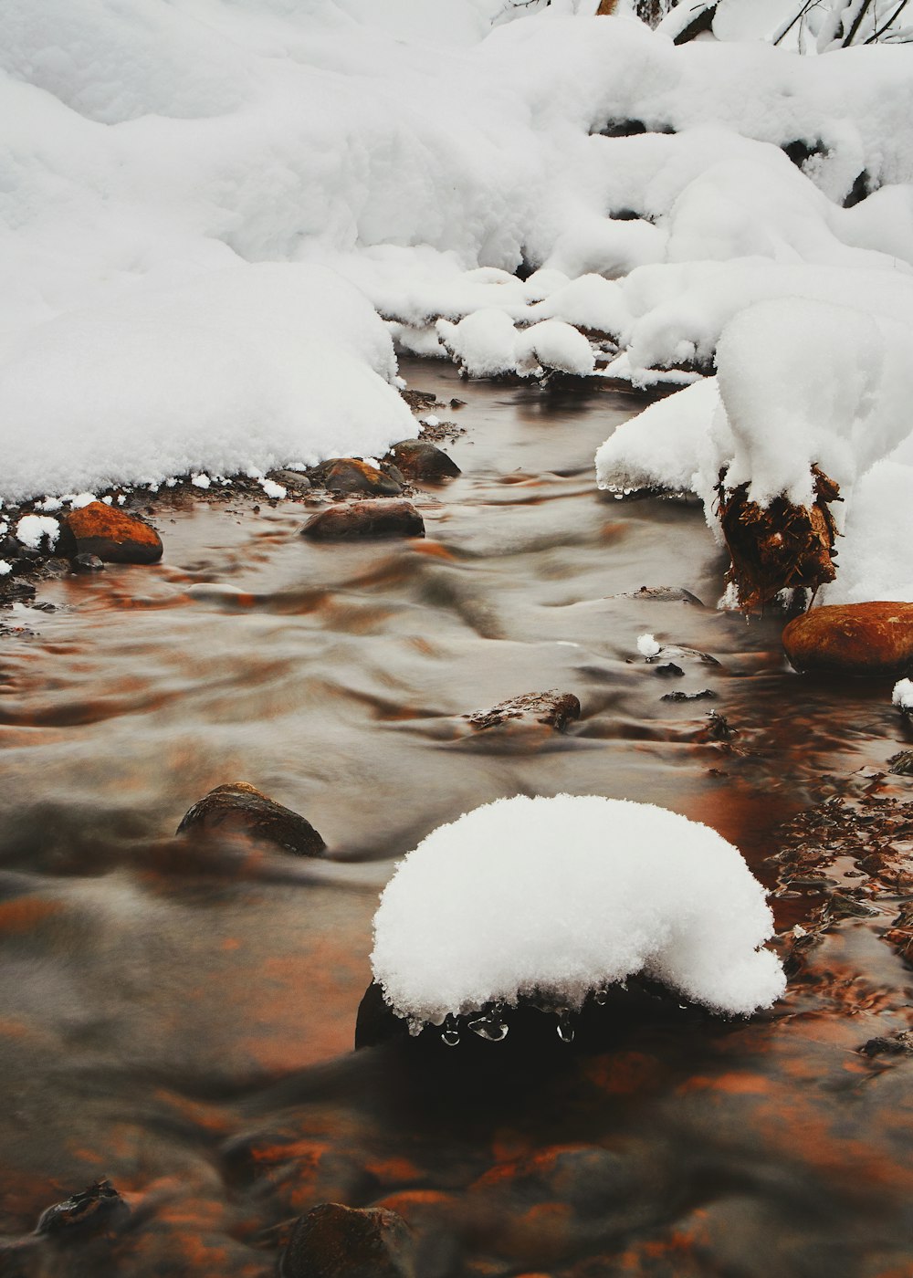 snow covered rocks on river during daytime