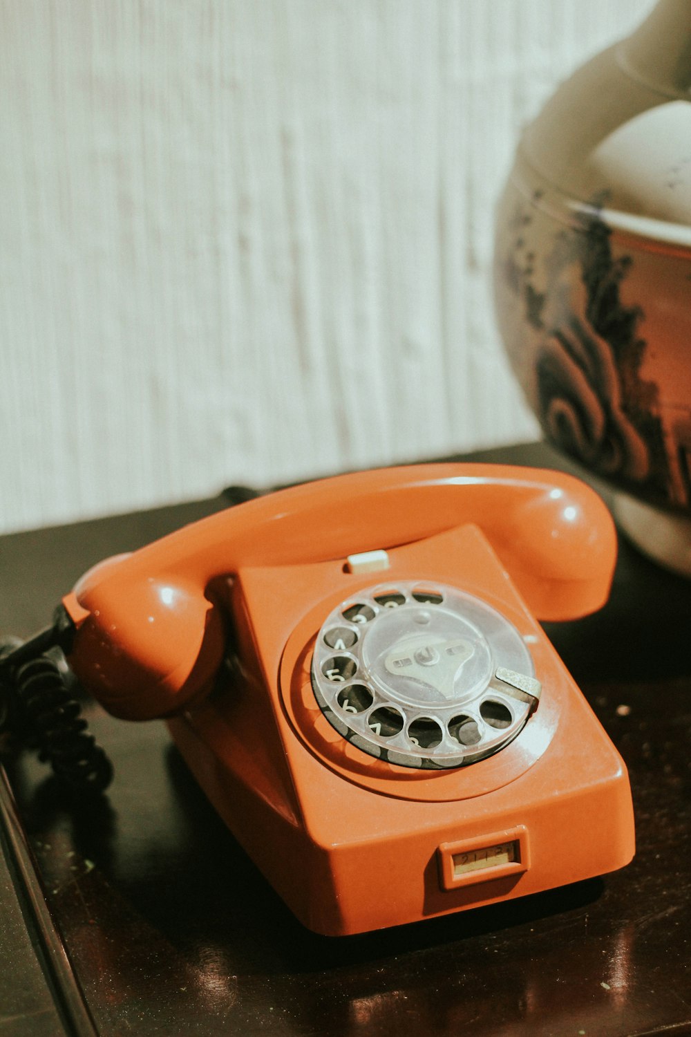 red rotary telephone on brown wooden table