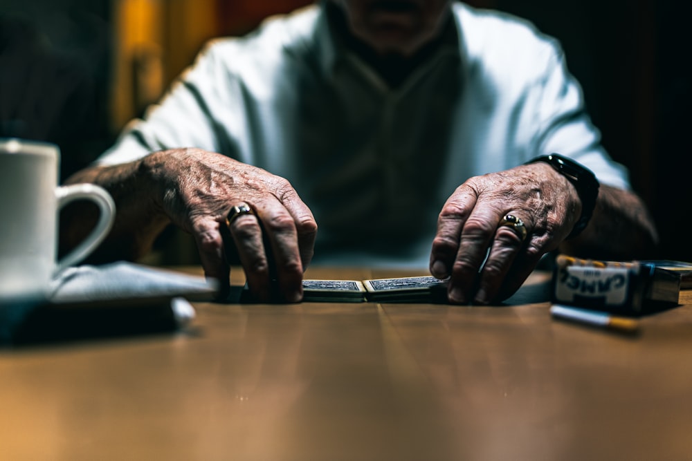 man in white dress shirt using macbook pro on brown wooden table