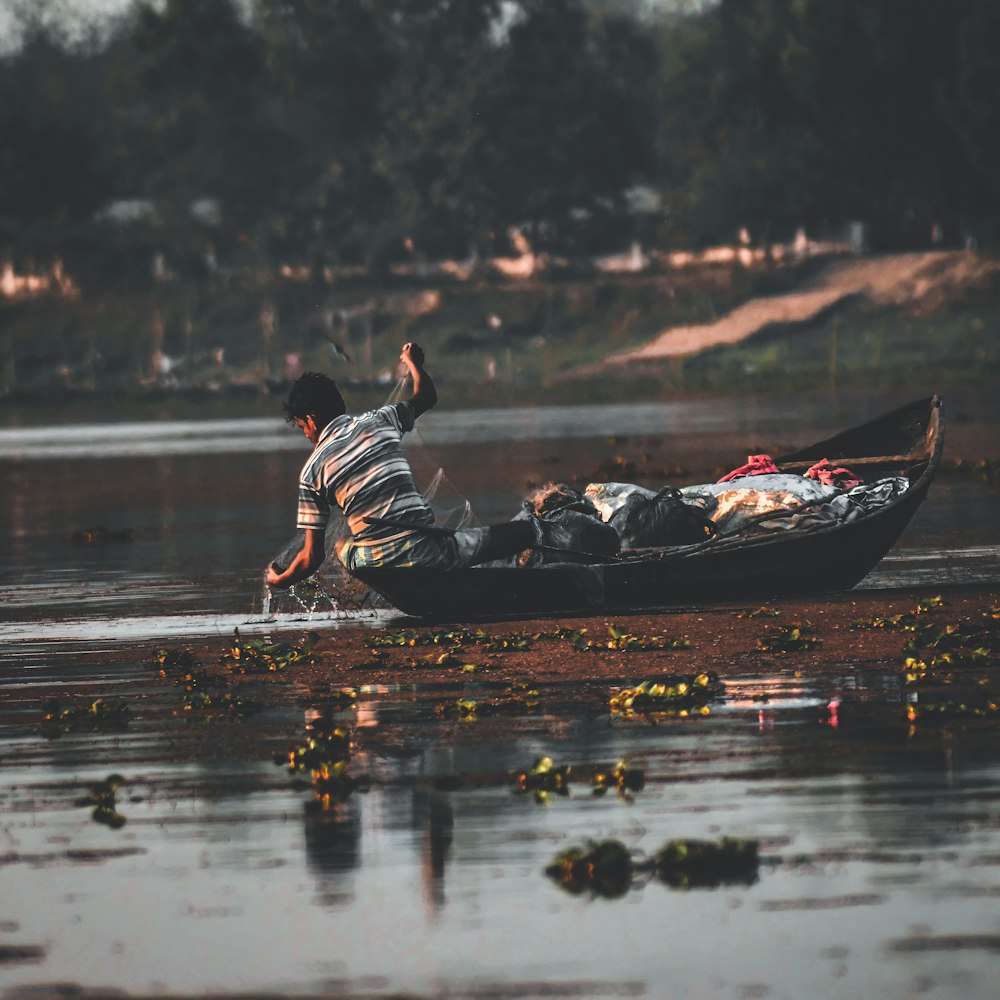 man in black and white striped shirt riding on black and red boat on water during