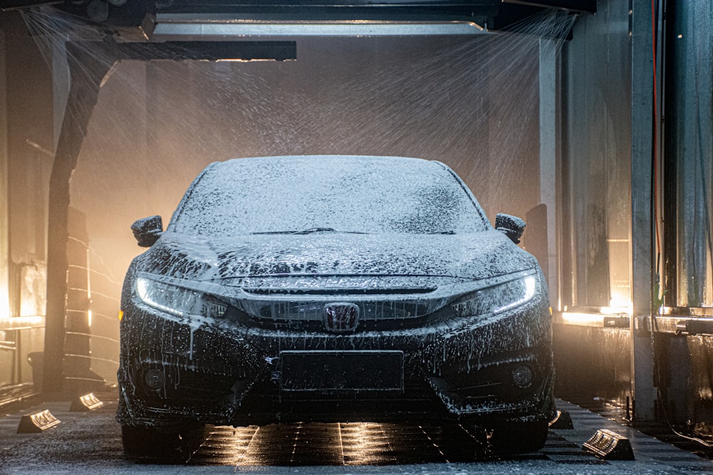 Une voiture est recouverte de neige dans un garage