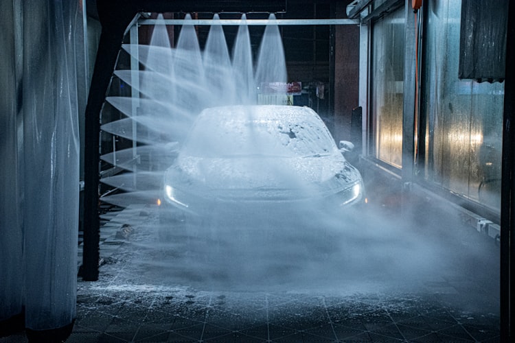 Car going through touchless car wash with water streams cleaning it