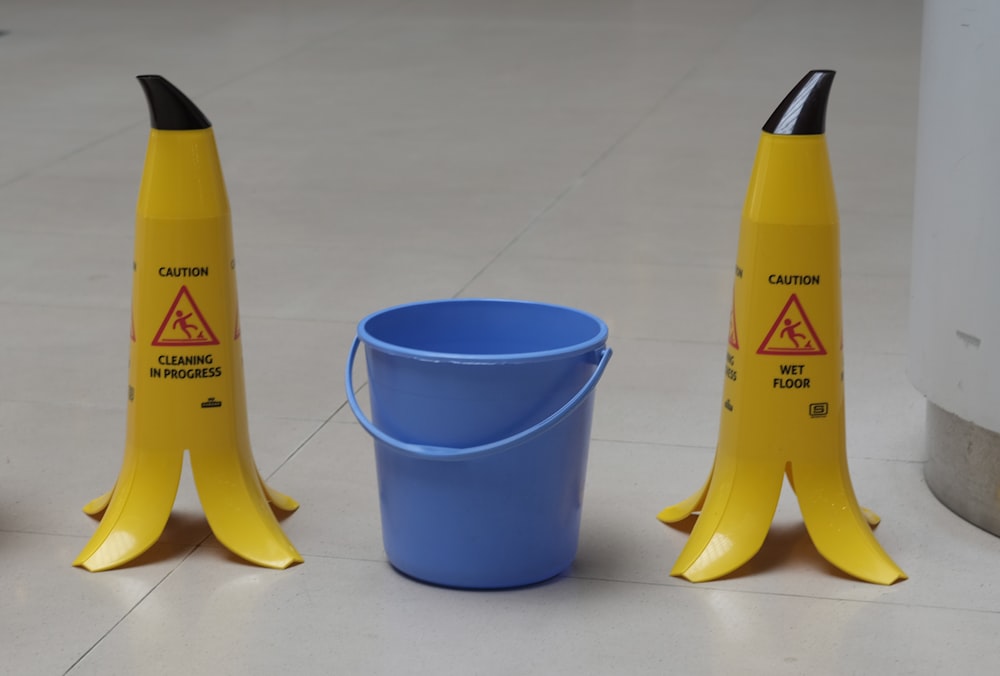Botella de plástico amarilla y negra junto a vaso de plástico azul