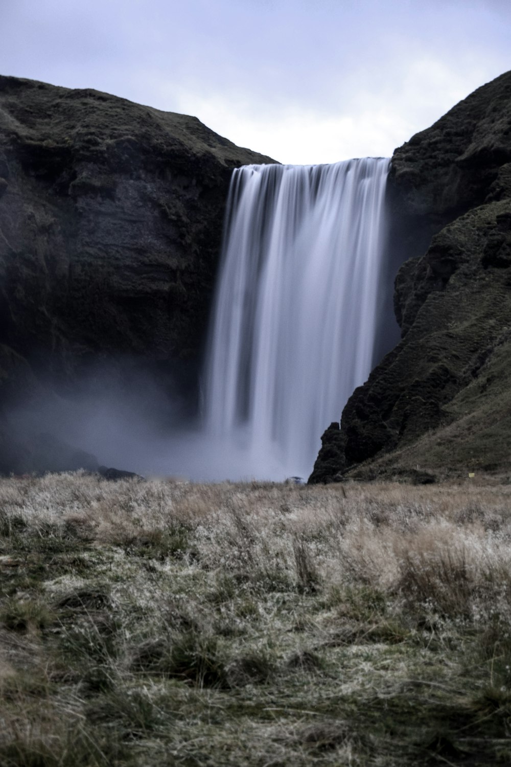 waterfalls on brown and green grass field during daytime