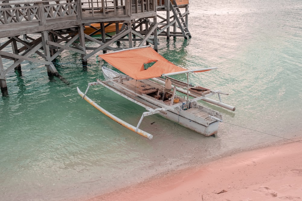 white and red boat on sea shore during daytime