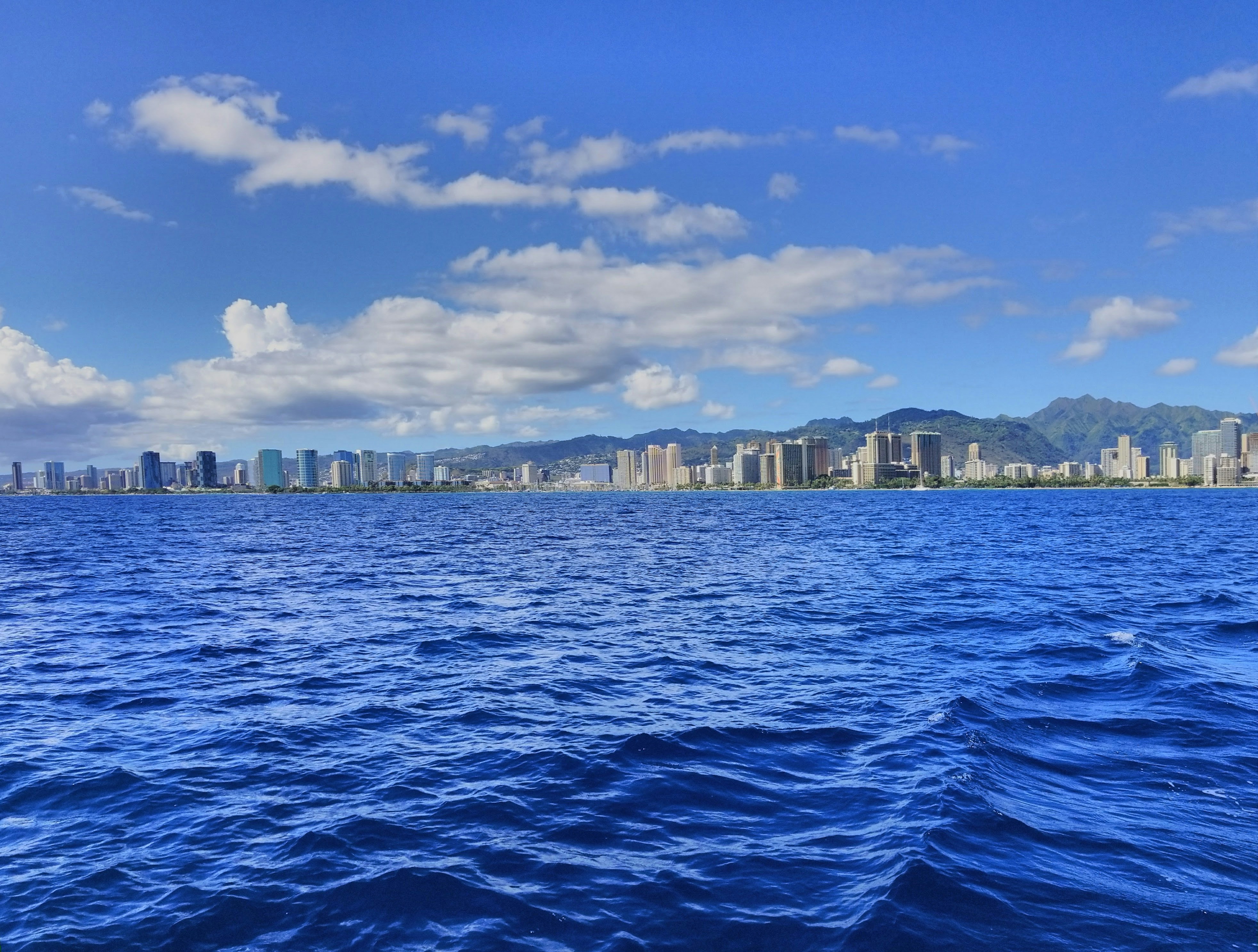 body of water near city buildings under blue and white sunny cloudy sky during daytime