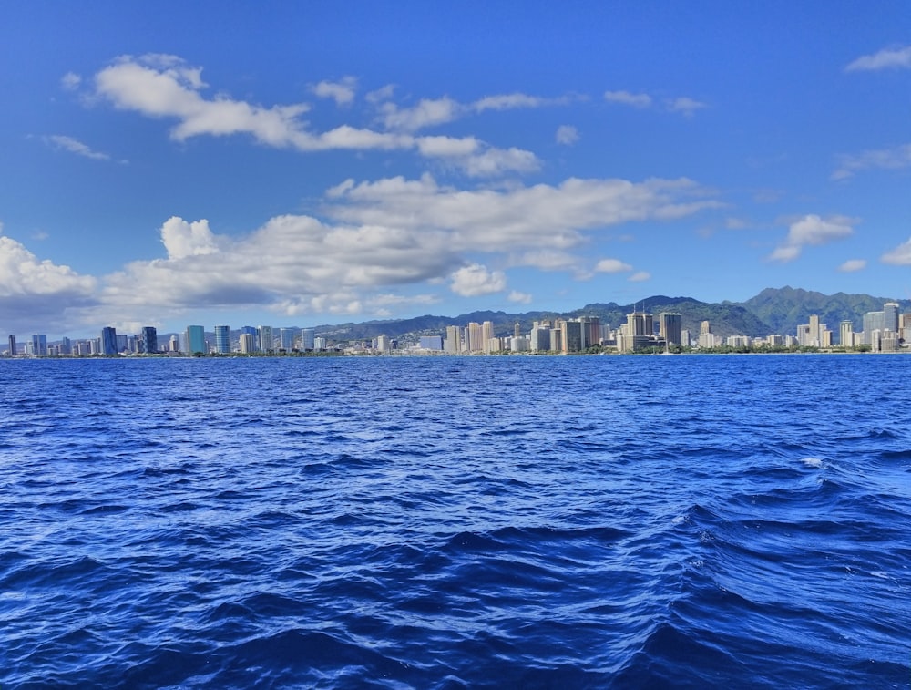 body of water near city buildings under blue and white sunny cloudy sky during daytime