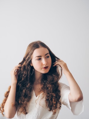 A serene woman gently brushing her long, smooth hair in front of a mirror.
