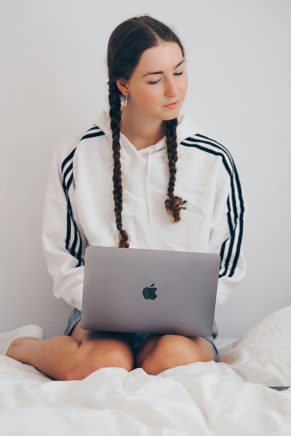 woman in white and black long sleeve shirt using silver macbook