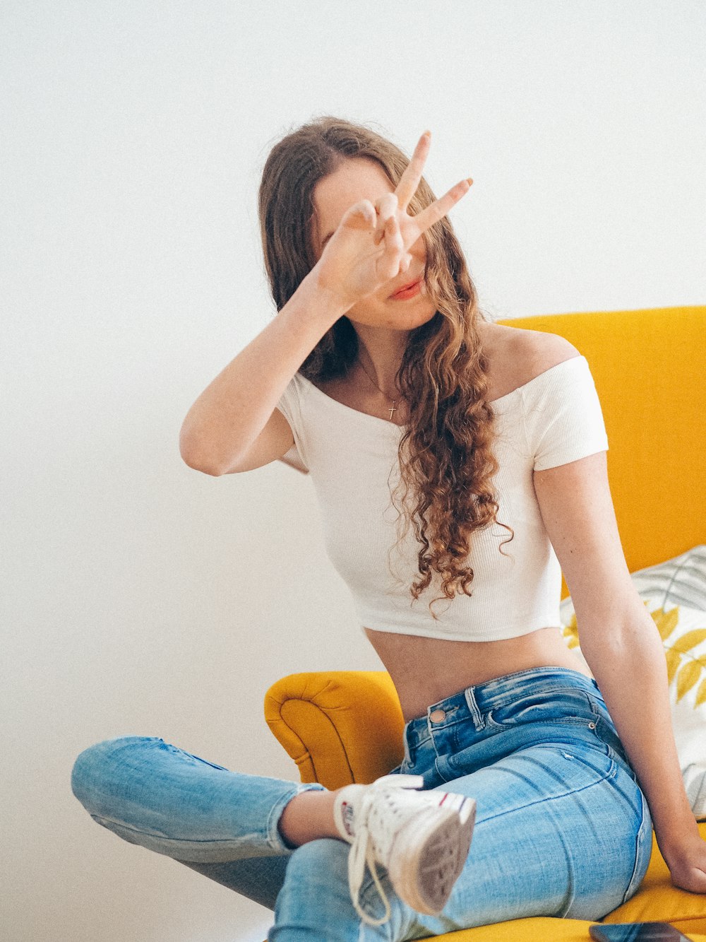 woman in white tank top and blue denim shorts sitting on yellow couch