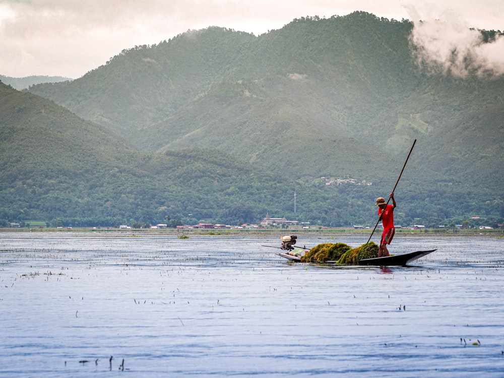 man in red shirt riding on boat on lake during daytime