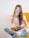 woman in white tank top and blue denim jeans sitting on yellow chair