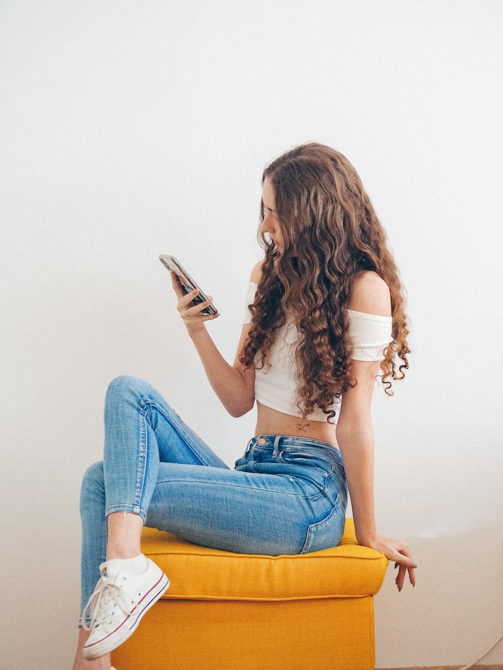 woman in blue denim jeans holding white ceramic mug