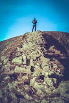 person in black jacket standing on brown rock mountain during daytime