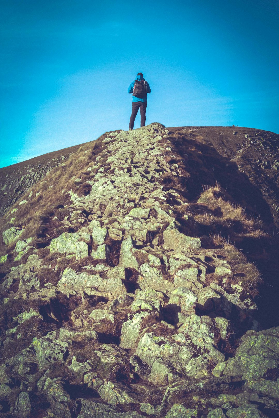 person in black jacket standing on brown rock mountain during daytime