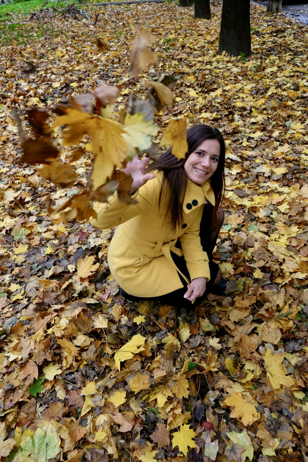 woman in yellow coat lying on dried leaves