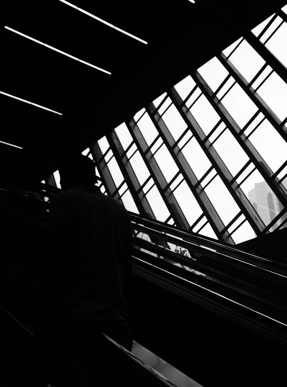 grayscale photo of man in suit jacket standing near window