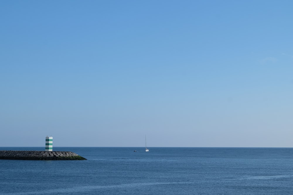 white and black lighthouse on sea under blue sky during daytime