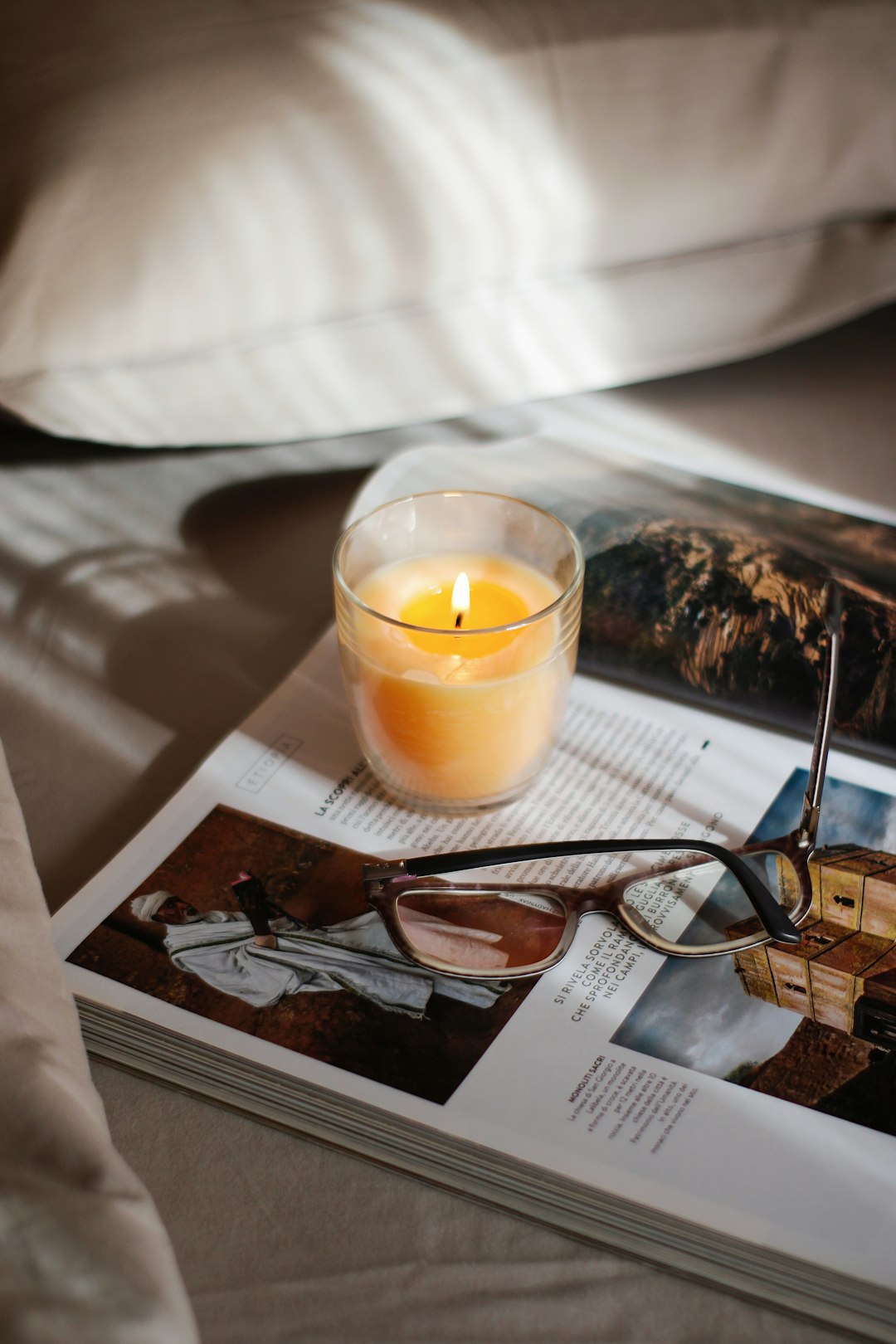 black framed eyeglasses beside clear glass cup on white book page