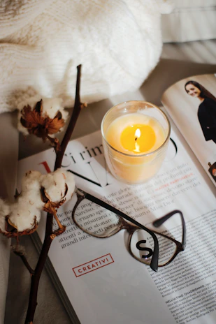 A cozy candle flickering beside a stack of old Kentucky novels and a sprig of bluegrass.