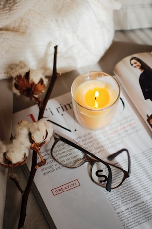 A corner of a room featuring a cozy rug, a basket of magazines, and a softly flickering candle.