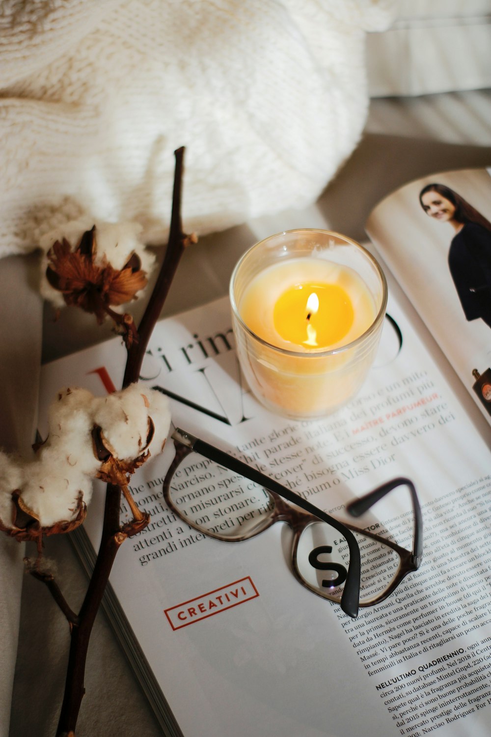 black framed eyeglasses beside white candle