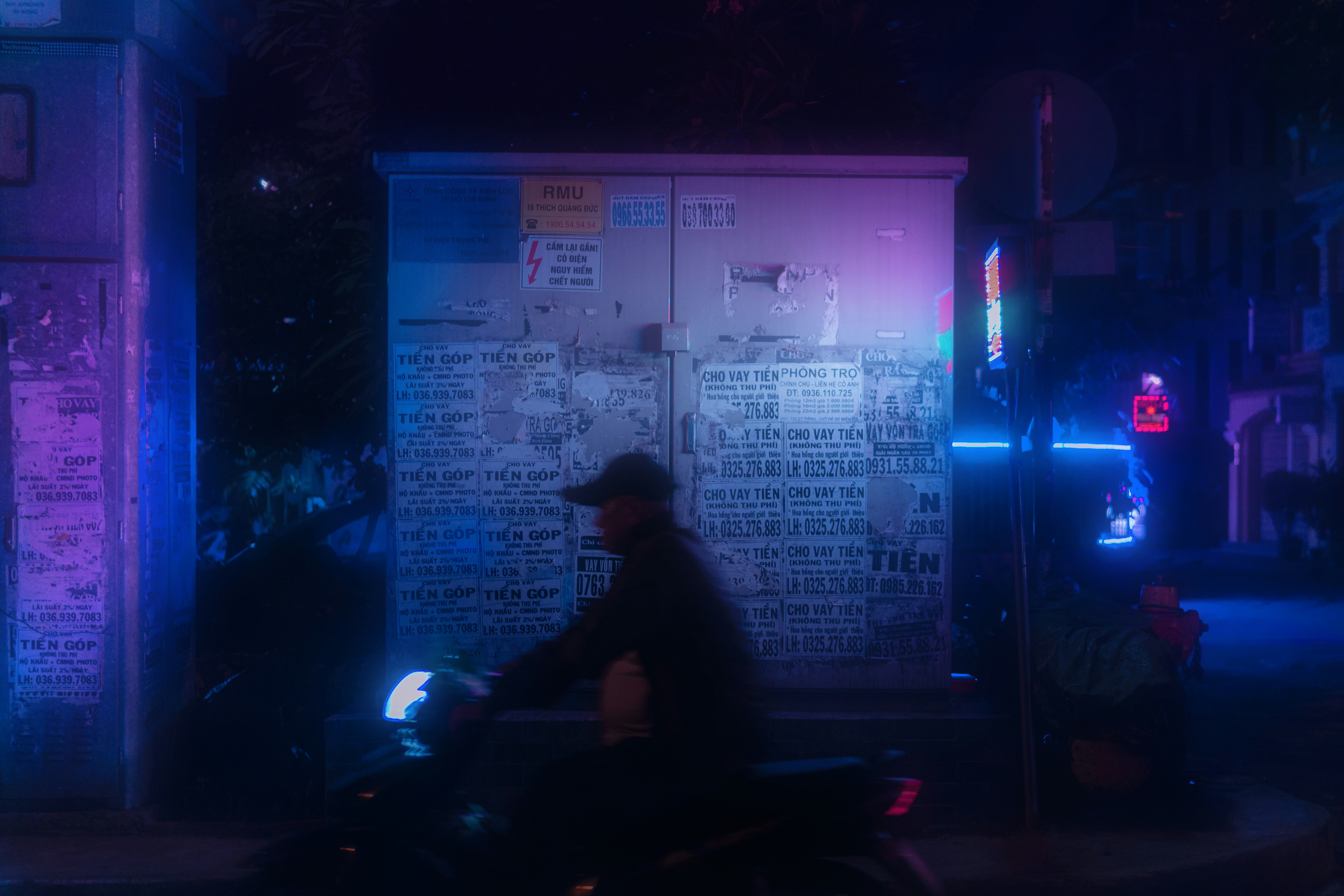 man-in-black-jacket-standing-near-white-and-blue-poster-during-nighttime