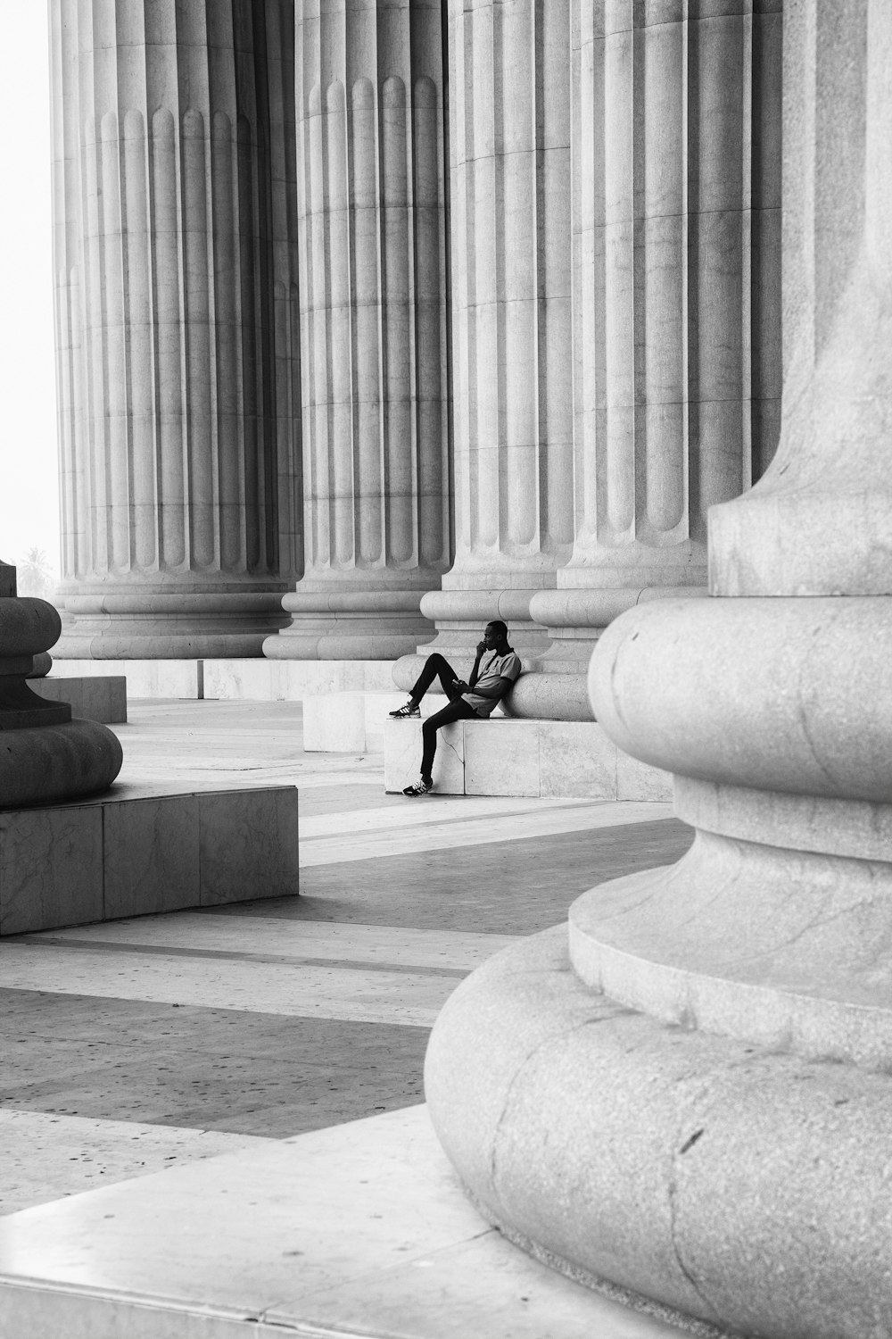 homme en veste et pantalon noir assis sur un banc en béton