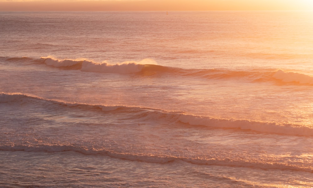 ocean waves crashing on shore during sunset