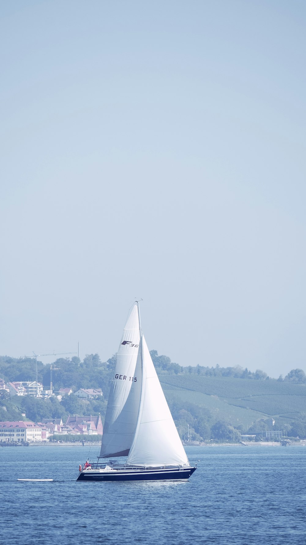 昼間の海上に浮かぶ白い帆船