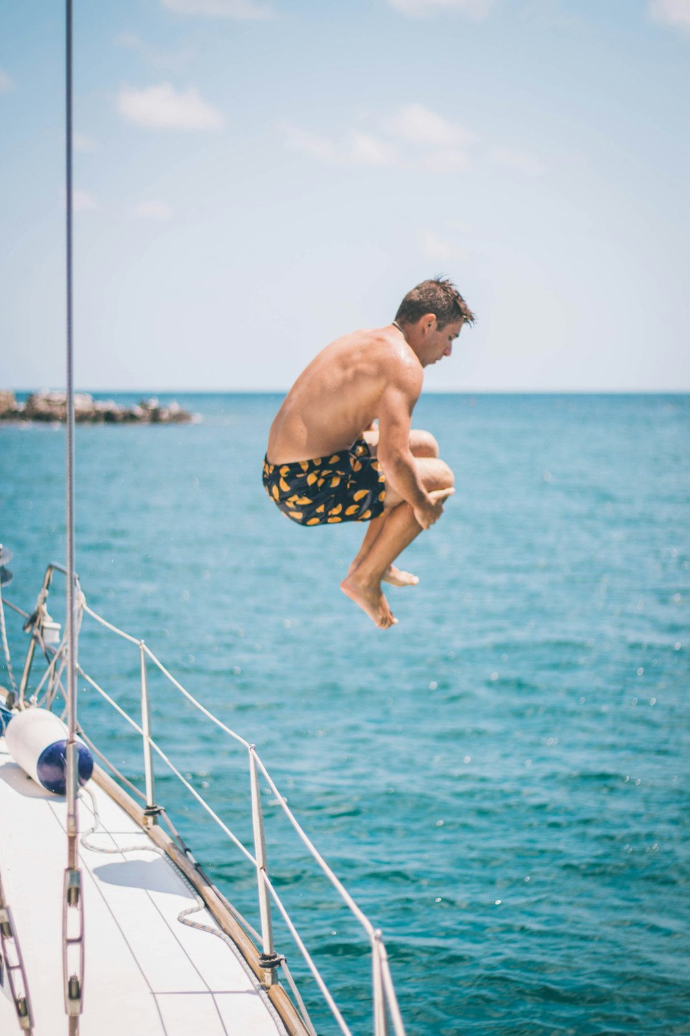 man in blue and white shorts standing on white boat during daytime