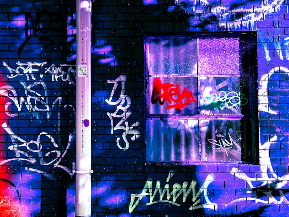 purple and white graffiti on black brick wall