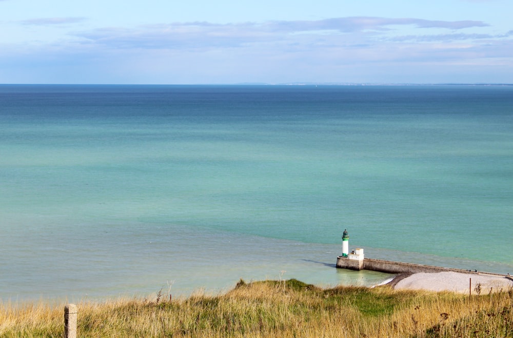 white lighthouse near body of water during daytime