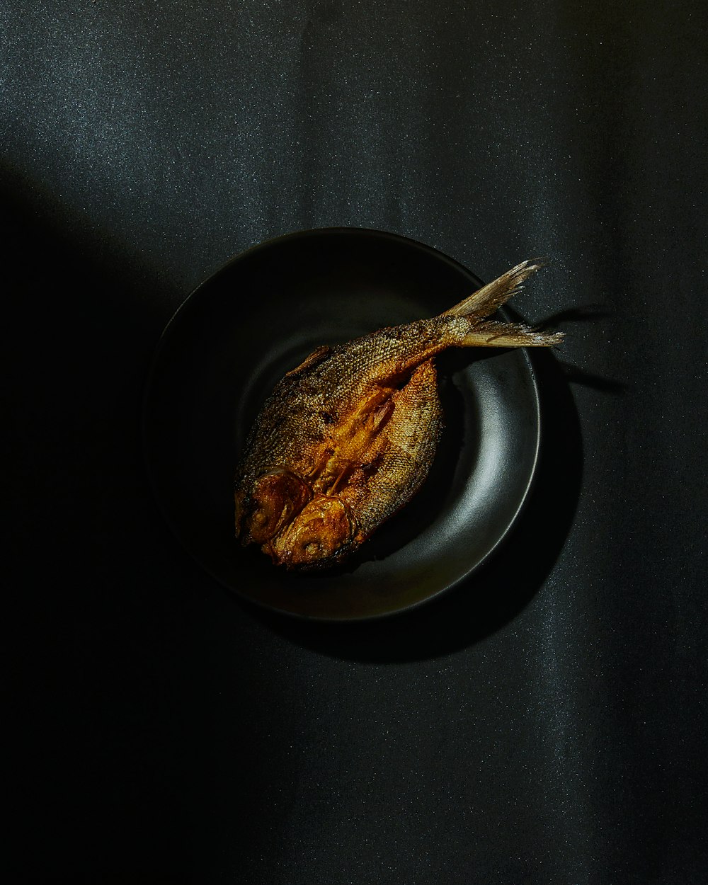 fried fish on black round plate