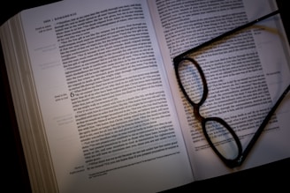 Open academic books showing pages on philosophy and history with a pair of reading glasses.