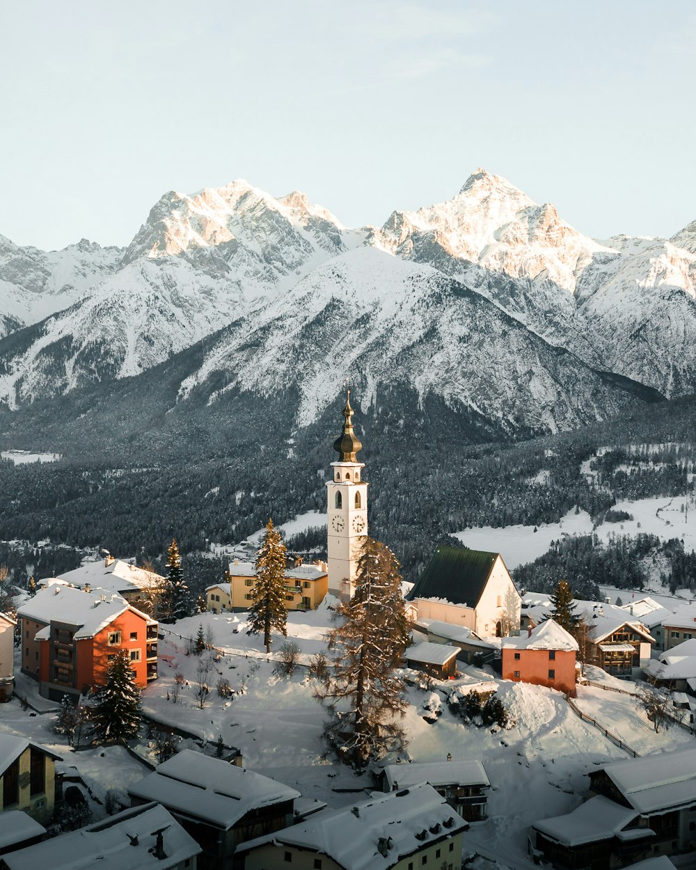 white and brown concrete building near snow covered mountain during daytime