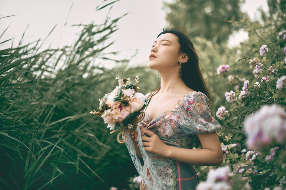 woman in blue and white floral dress holding white flowers