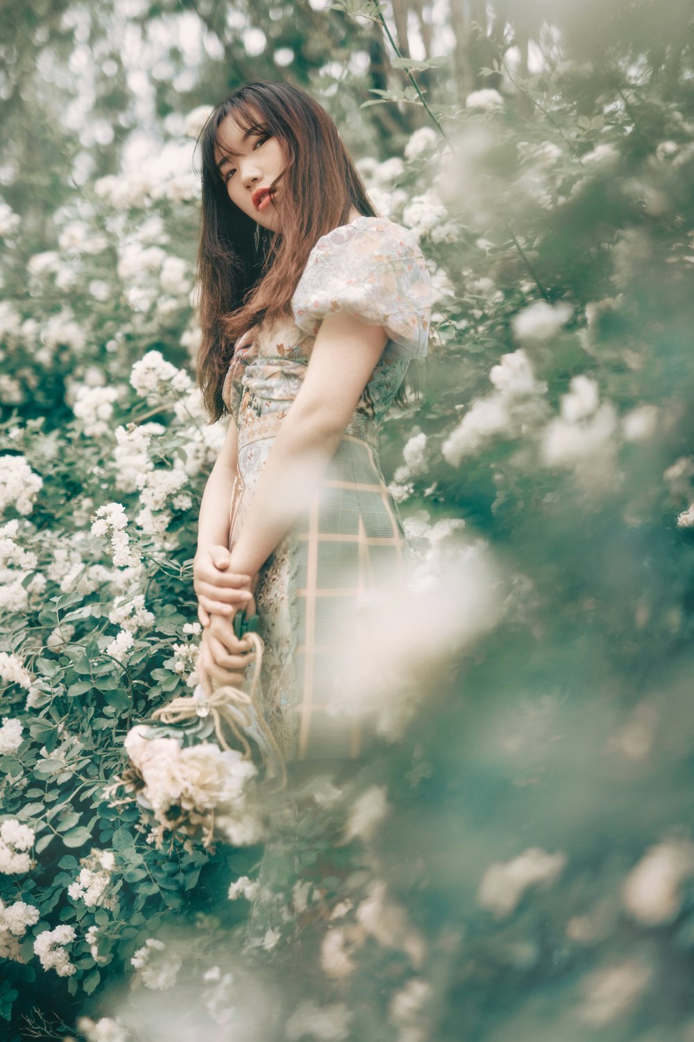 woman in white dress holding white flower bouquet