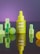 A neon yellow dropper bottle labeled 'not pot CBD Glow Oil' is centrally positioned, surrounded by geometrically shaped translucent objects including cubes and spheres. The background has a gradient of purple, adding a vibrant contrast to the foreground elements.