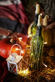 green glass bottle beside lighted candle
