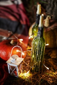 green glass bottle beside lighted candle