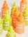 A collection of vibrant bottles with droppers in bright neon green and orange hues. Each bottle is labeled with 'not pot' and is part of a CBD product line, including glow oil and pet CBD oil.