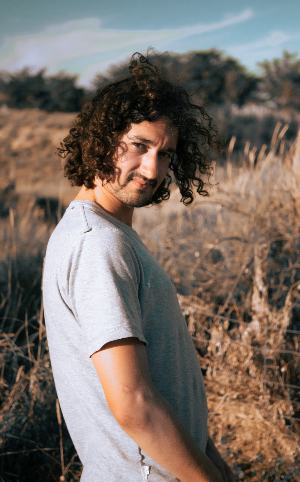 man in gray crew neck t-shirt standing on brown grass field during daytime