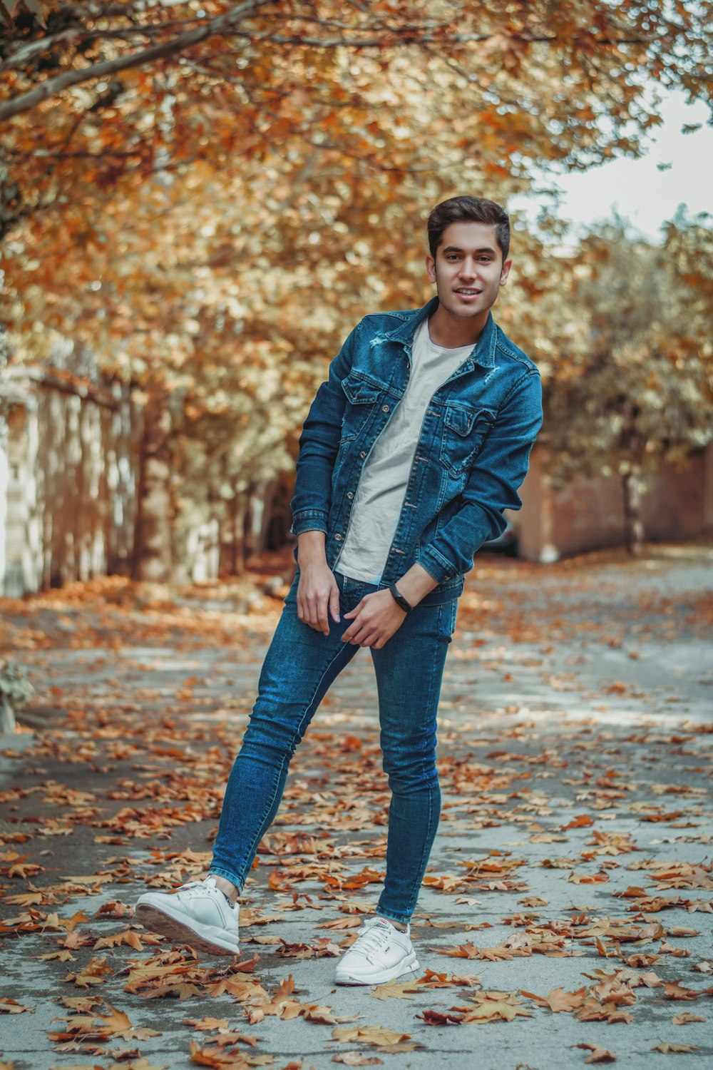 woman in black leather jacket and blue denim jeans standing on road during daytime