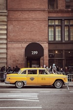 Clean, black and yellow taxi waiting in front of a modern office building.